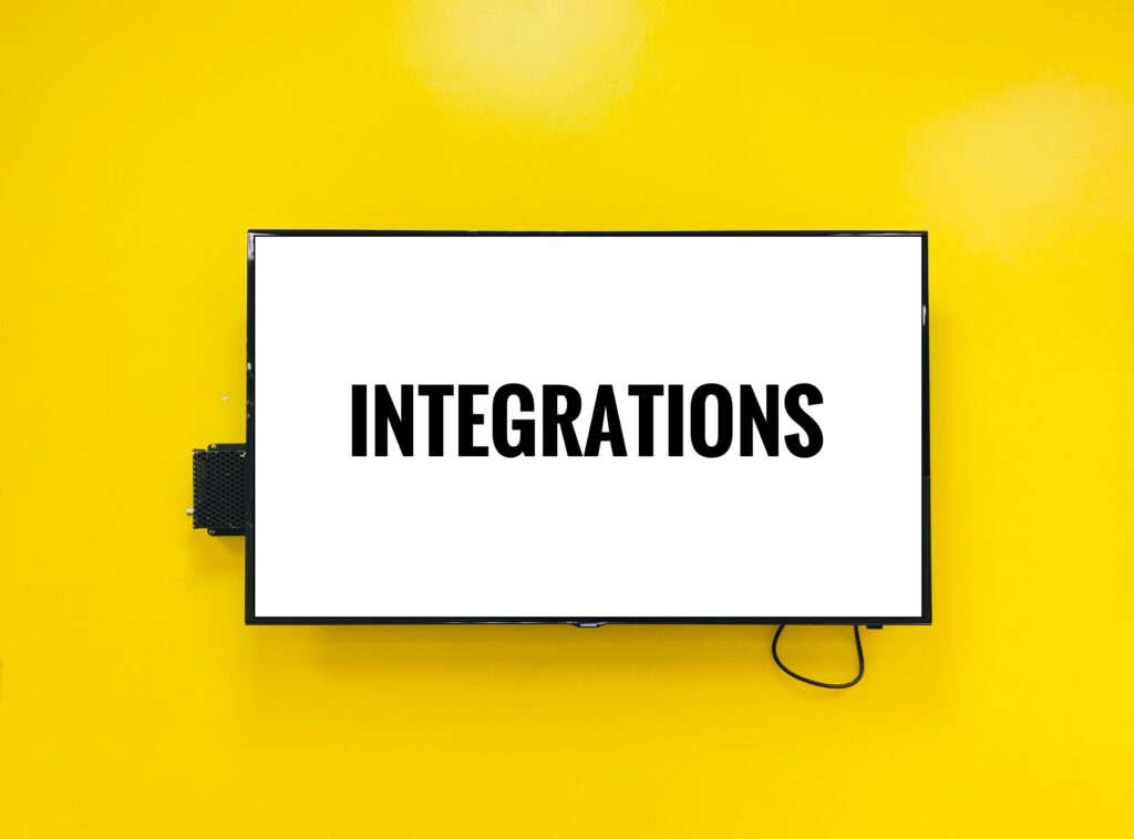 Napis "Integrations" na telewizorze z białym tłem, który widzi na żółtej ścianie. 